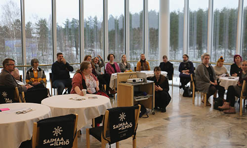 Koordinaattori esittelee Saimaa-ilmiötä videotykiltä. Tilaisuudessa jaettiin osallistujille mainoskassit, joissa lukee Saimaa-ilmiö.