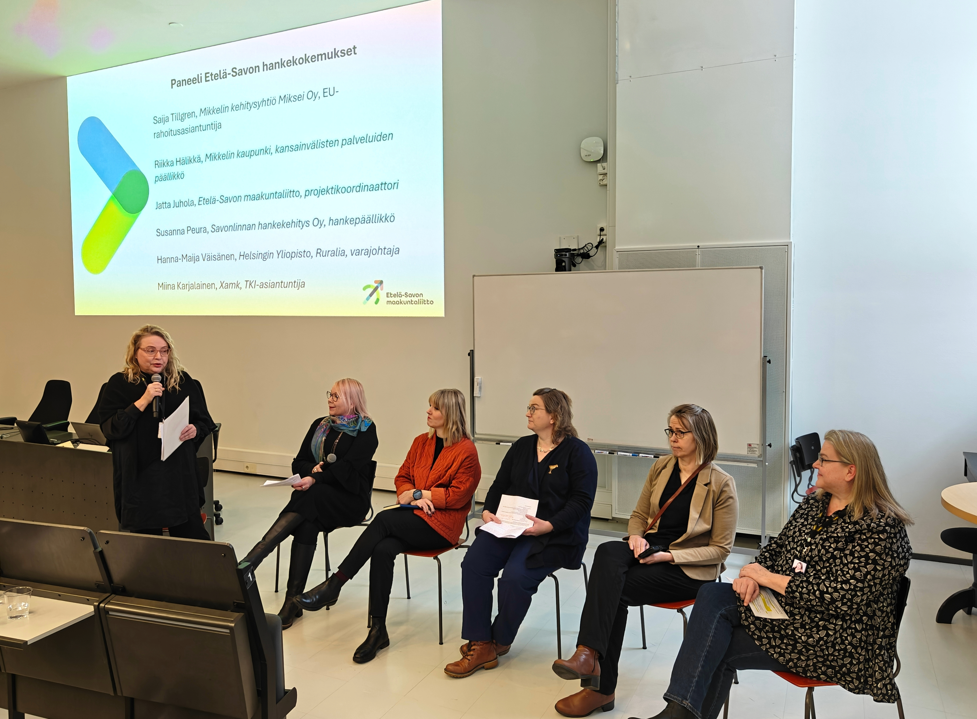 Paneelikeskustelun osallistujat salin edessä.