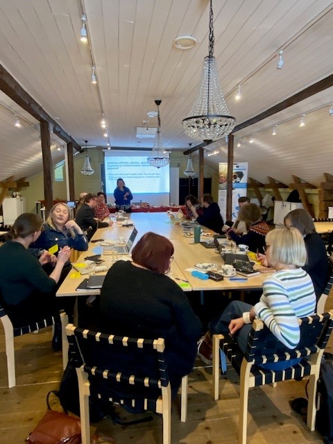 Ihmisiä työpajassa pöydän ääressä.